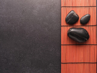 Three massage stones on a bamboo mat