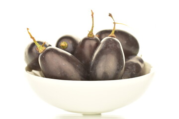 Several berries of black grapes in a white saucer, close-up, isolated on white.