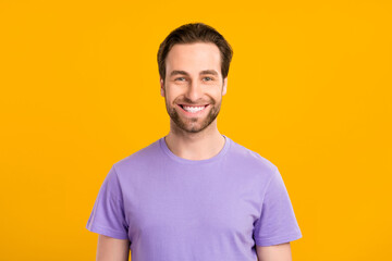 Photo of positive handsome guy look camera toothy beaming smile wear purple t-shirt isolated yellow...