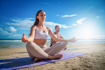 Fototapeta na wymiar Young healthy Yoga woman and man workout yoga pose on the beach at daytime