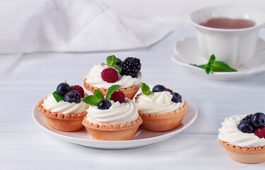 Mini tartlets with whipped cream and fresh berries, on a white table, blurred focus, horizontal, no people,