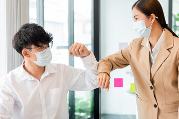 two business partners wearing protective mask touching elbows together agreed to work on the new project