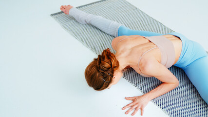 Young yoga coach doing gymnastics on a yoga mat