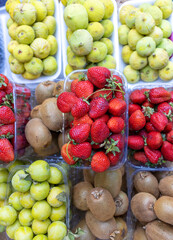 Lots of fresh berries and fruits on the counter at the farmers market. Red strawberries, kiwi and...