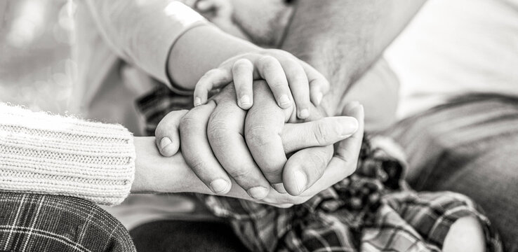 Concept of unity, support, protection, happiness. Child hand closeup into parents. Hands of father, mother, keep hand little baby. Black and white