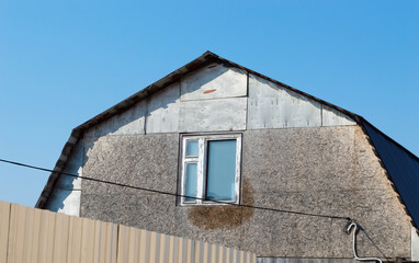 house with an attic with a rough finish made of wooden panels, a window in the center