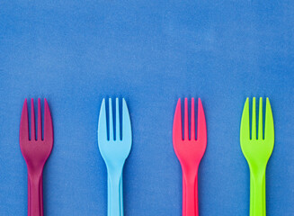 colorful plastic forks on color background with copy space