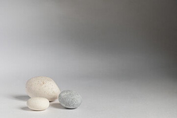 Fototapeta na wymiar Three grey stones with a shadow on grey background.