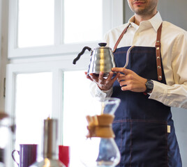 man in barista apron holding coffee pot