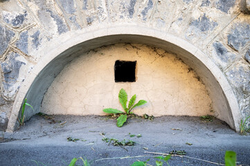 Antique arched basement window, with stucco molding, walled up and left a small ventilation hole. 