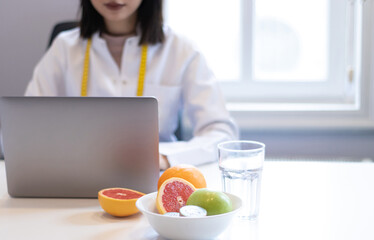 dietitian woman working with her computer and an office with mixed fruit and water on the table