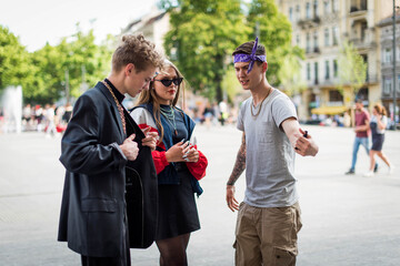 Cute fun curly teenage boy, girl and man wearing stylish 90s fashion clothes with chains around...