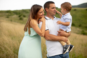 Young family with cute little boy having fun outdoors in the field