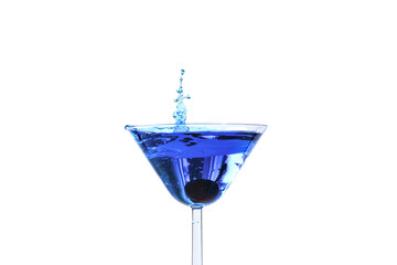 Cocktail with blue liquid in glass. Glass with blue water pouring with liquid with splashes and drops. Martini glass filling with alcohol with splashes on white background. Refreshing drink concept.
