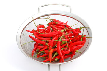 Group of fresh red hot chilli peppers in metal basket on white background