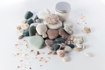 body and soul care banner, colored round stones, sea salt cream body peeling on white background