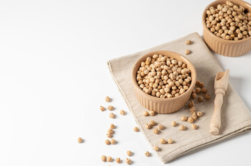 dry chickpeas, in a ceramic bowl on a white table, empty space for text