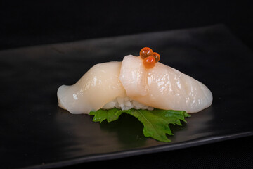 One Japanese fresh Sushi nigiri with scallop on black background, close up. © Nuttanun