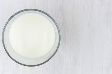 Glass of milk on a white wooden table. Top view.