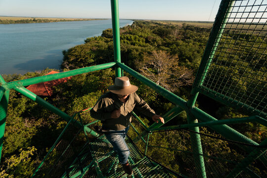 Hombre sube a una torre de vigilancia a un costado de un r&iacute;o caudaloso al aire libre 