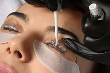 Young woman undergoing eyelash lamination, closeup. Professional service