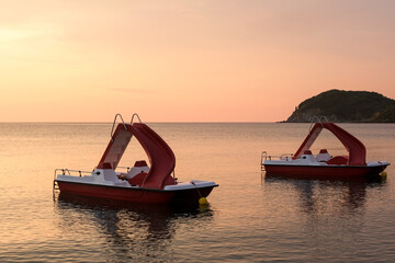Two pedal boats at splendid sunset 
anchored to the shore of Baratti beach. Scenery of the Val di Cornia. Tuscany
