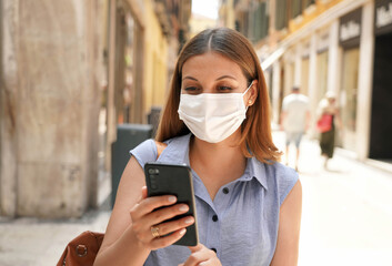 Beautiful woman watching her smartphone in city street. Travels with digital covid certificate.