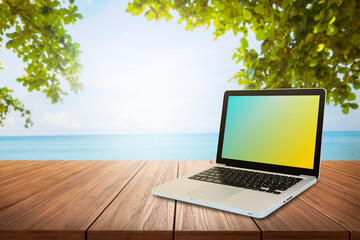 laptop on a wooden table by the sea Concept for work anywhere with internet technology.