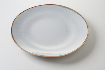 Empty generic white pottery plate or disg with narrow brown rim