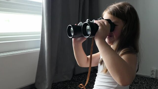 girl looks in black binoculars optical instrument 