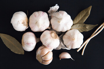 Garlic with spices and bay leaf on a black background, top view. Food background.