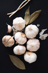 Aromatic garlic bulbs with spices, bay leaves and peppercorns on a black background. Condiments and spices. Natural remedies for strengthening immune system.