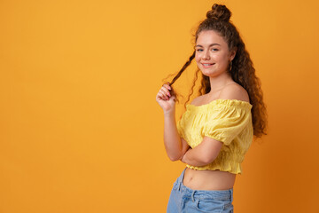Portrait of a young curly-haired woman against yellow background