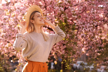 Young woman wearing stylish outfit in park on spring day. Fashionable look - obrazy, fototapety, plakaty