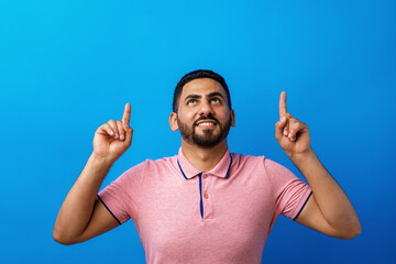 Young handsome arab man over beige background pointing to copy space and smiling