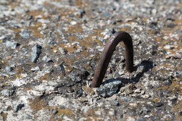 Rusted metal bracket into old concrete slab close-up, on sunny day