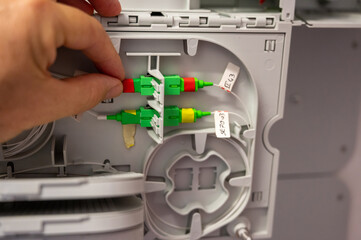 A technician at work: close up shot of the hand checking the cabling of the optical fibers inside the distribution box.