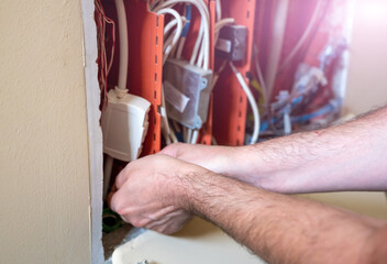 Obraz premium A telephone junction box has been opened: a technician from the network operator is inserting an optical fiber in the pipe to connect to the data network of an apartment.