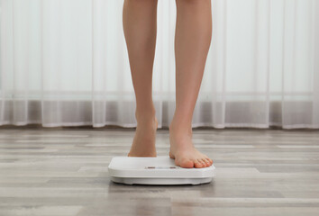 Woman stepping on floor scales indoors, closeup. Weight control - obrazy, fototapety, plakaty