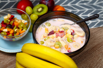 A bowl of a sweet yogurt with fruit. Organic diet yogurt with bananas, kiwi, peaches, plums, apricots