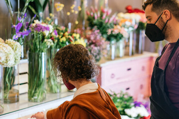 Young woman with mask choosing flowers in a flower shop.