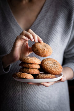 A person in a sweater holding a plate of cookies.