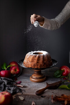 Bundt cake on a cake stand being sprikled with powdered sugar