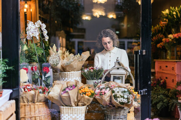 Young girl behind a window of a flower store selecting bouquets.