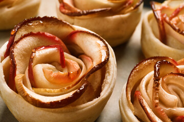 Obraz na płótnie Canvas Freshly baked apple roses on parchment paper, closeup. Beautiful dessert