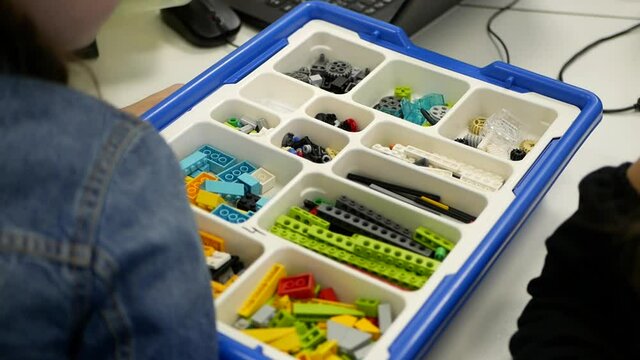 Close-up of a student's hand in an engineering class making a robot. Robotics education. Children play with toys from building blocks. Colorful constructor in a box. An entertaining educational game.