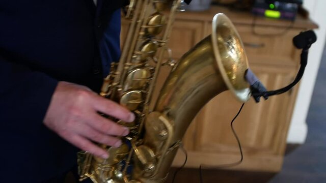 Close-up of the hands of a saxophonist playing the saxophone during an off-site wedding ceremony or holiday event.