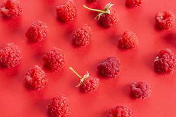 Ripe raspberry fruits, healthy pile of summer berries  top view. 
Pattern flat lay of red scarlet  raspberry on red background with free copy space for text