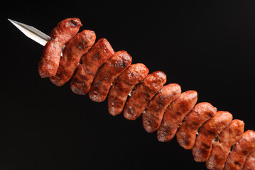 Barbecue sausages on skewers on black background.