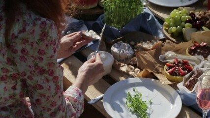 woman spreads soft cheese on a piece of bread